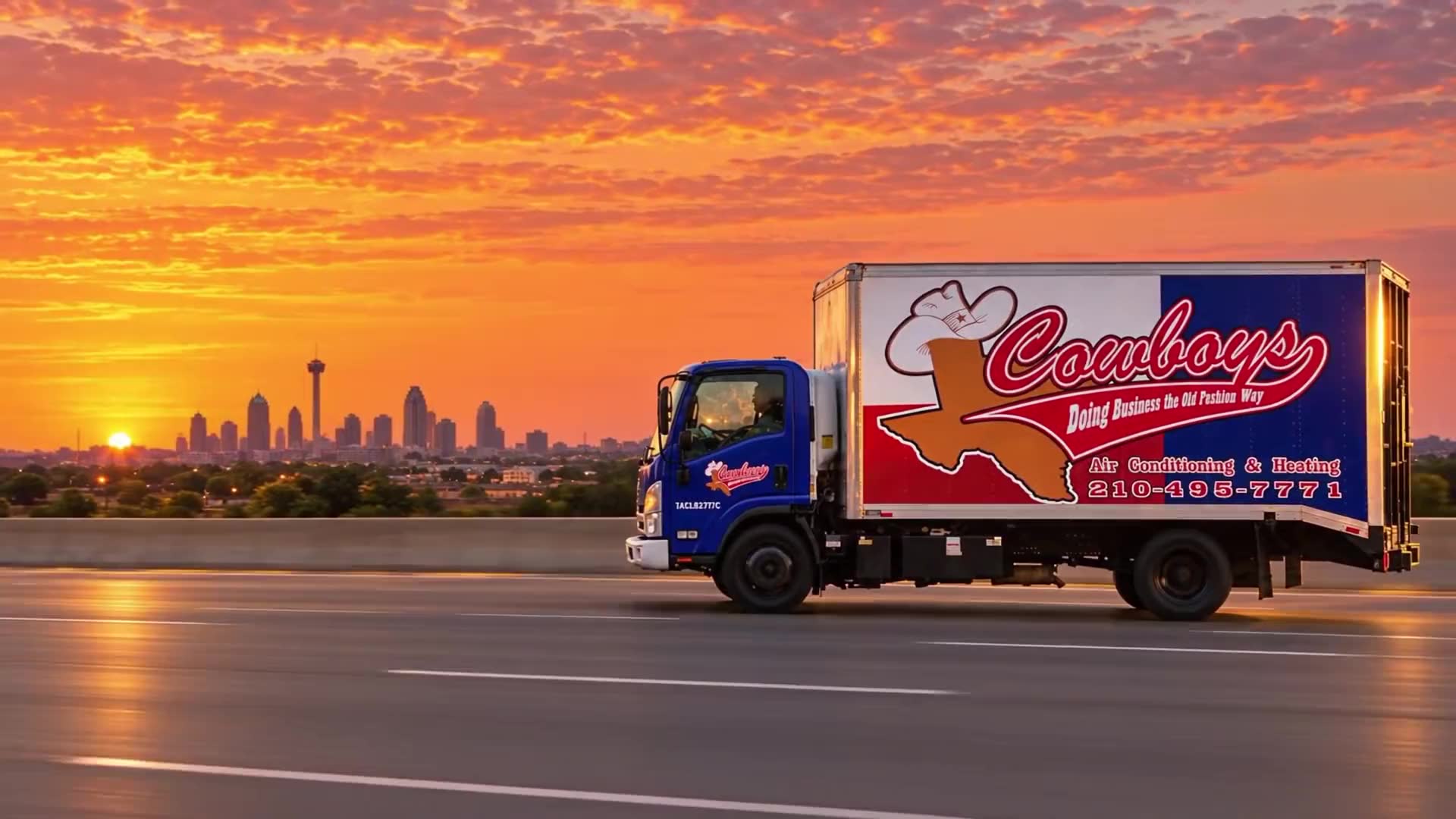 The Cowboy's Air Conditioning & Heating box truck on the highway at sunset with the San Antonio skyline behind it