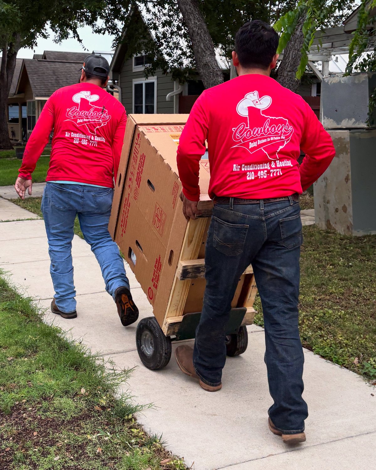 Two Cowboy's techs wheeling new equipment up to a customer's house
