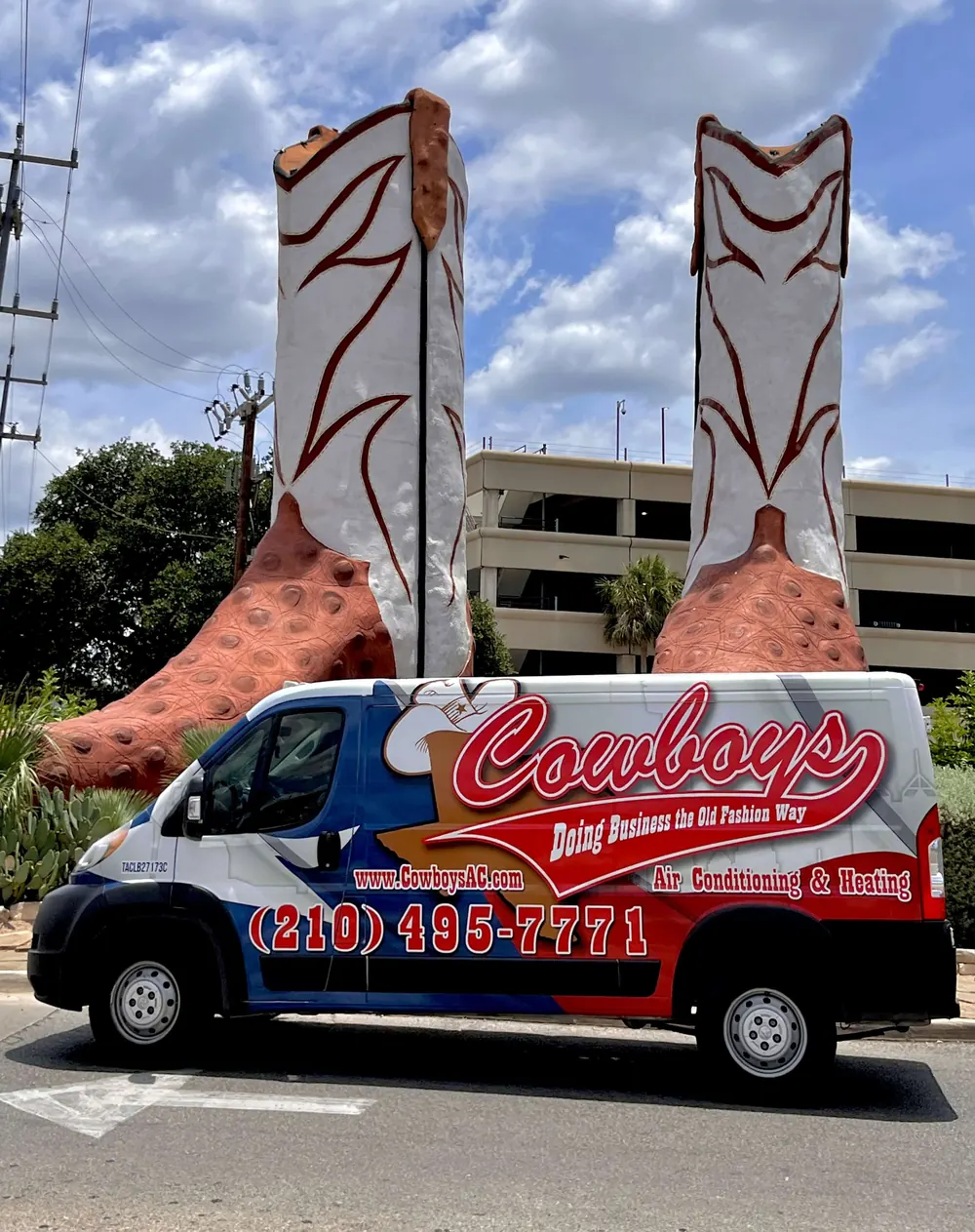 A Cowboy's van parked in front of a pair of giant cowboy boot sculptures